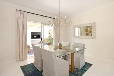a dining room with a glass table and white chairs at The Farm Cottage in Franschhoek