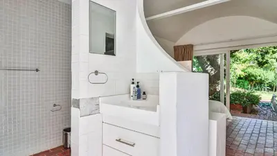 a white bathroom with a sink and a mirror at Birdsong in Hermanus