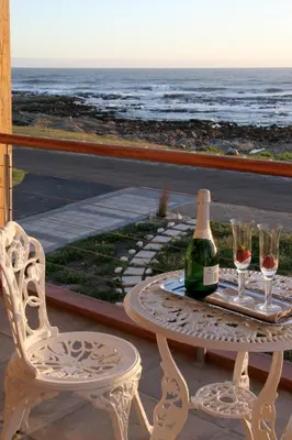 a table with a bottle of wine and two glasses at 138 Marine Beachfront Guesthouse in Hermanus