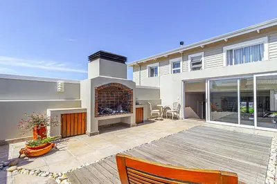 a house with a patio with a fireplace at 138 Marine Beachfront Guesthouse in Hermanus