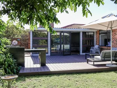 a patio with an umbrella and a table and chairs at Sandbaai Breeze in Hermanus