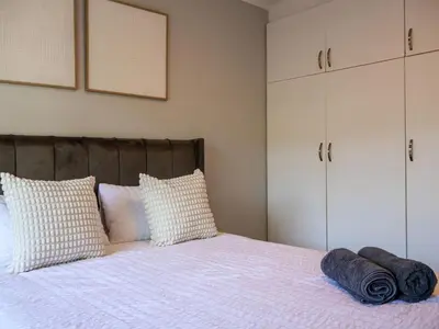 a bedroom with a large bed with pillows and cabinets at Sandbaai Breeze in Hermanus