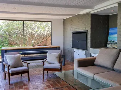 a living room with a couch and chairs and a television at Sandbaai Breeze in Hermanus