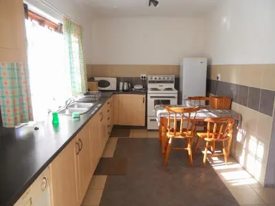 a kitchen with a table and chairs and a stove and refrigerator at Twin Oaks Lodges in Cape Town