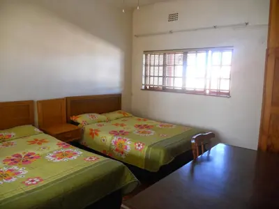 two beds in a small room with a window at Twin Oaks Lodges in Cape Town