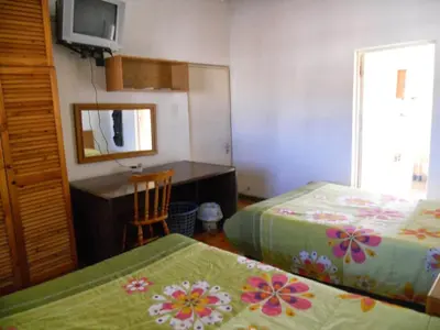 a bedroom with two beds and a desk and a mirror at Twin Oaks Lodges in Cape Town