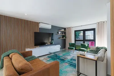 a living room with a couch and a flat screen tv at Sunset Sundowners Villa in Cape Town