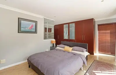 a bedroom with a large bed and wooden cabinets at Sunset Sundowners Villa in Cape Town