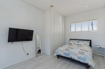 a bedroom with a bed and a flat screen tv at Sunset Sundowners Villa in Cape Town
