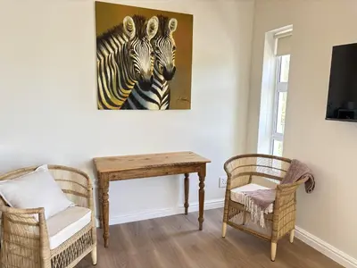 a room with a table and a painting of zebras at Golden Hillside in Somerset West