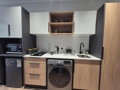 a small kitchen with a washing machine and a dishwasher at Trendy Studio Apartment in On Park in Cape Town