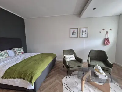 a bedroom with a bed and two chairs at Trendy Studio Apartment in On Park in Cape Town