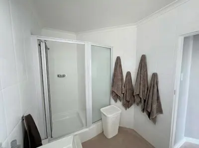 a white bathroom with a shower and a toilet at Odeon Ocean View in Strand