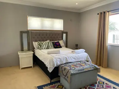 a bedroom with a bed with a headboard and a window at Blouberg kiters in Cape Town