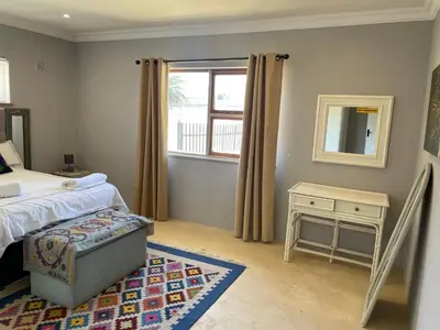a bedroom with a bed and a table and a window at Blouberg kiters in Cape Town