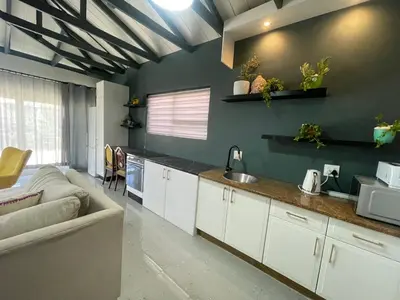a kitchen with white cabinets and a couch in a room at Blouberg kiters in Cape Town