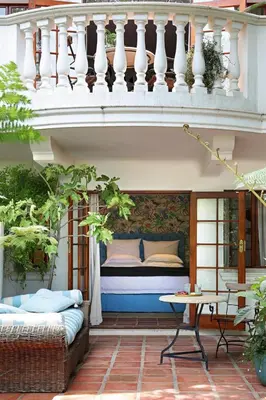 a bed on a patio under a balcony at Le Grand Jardin Villa in Kayamnandi