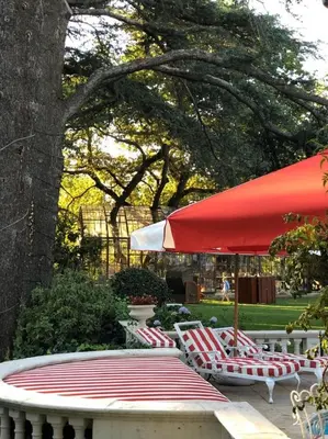 a group of chairs and a table with a red umbrella at Le Grand Jardin Villa in Kayamnandi