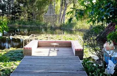 a bench sitting on a dock next to a lake at Le Grand Jardin Villa in Kayamnandi