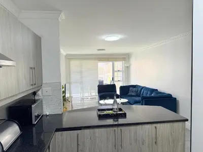 a kitchen and living room with a blue couch at Italian luxe 6 sleeper apartment near canal walk in Cape Town