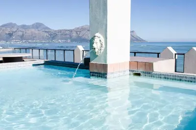 a swimming pool with the ocean in the background at The Strand Pavillion in Strand