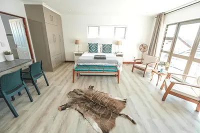 a bedroom with a bed and a table and chairs at Abalone at Hermanus Reefs in Hermanus