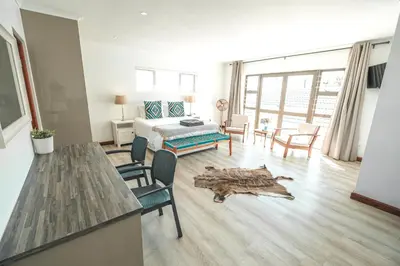 a room with a bed and a table and chairs at Abalone at Hermanus Reefs in Hermanus