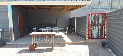 a patio with tables and chairs and a red door at Family Cottage no 4 in Wellington