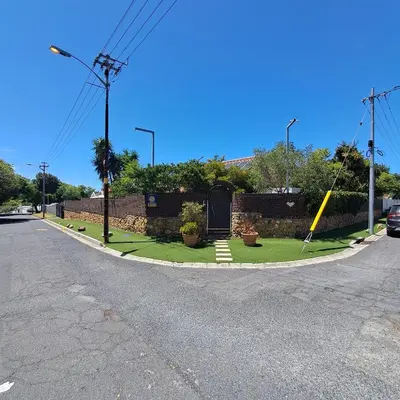 a curvy street with a retaining wall and a yard at Peaceful one bedroom guesthouse in Rondebosch in Cape Town
