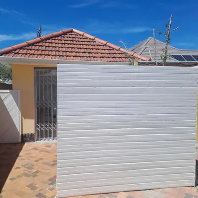 a white garage door in front of a house at Peaceful one bedroom guesthouse in Rondebosch in Cape Town