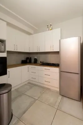 a kitchen with white cabinets and a stainless steel refrigerator at Mountain and Tides in Kleinmond