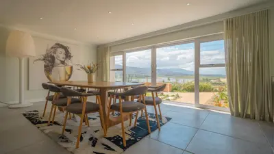 a dining room with a table and chairs and a large window at Swallows Rest - Benguela Cove in Hermanus