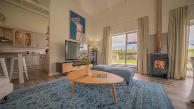 a living room with a table and a fireplace at Swallows Rest - Benguela Cove in Hermanus
