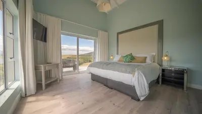 a bedroom with a large bed and a large window at Swallows Rest - Benguela Cove in Hermanus