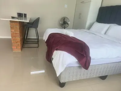 a bedroom with a bed and a table and a chair at On 10 breezand road in Cape Town