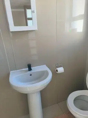 a white bathroom with a sink and a toilet at On 10 breezand road in Cape Town