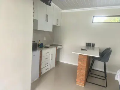 a small kitchen with a table and a chair at On 10 breezand road in Cape Town