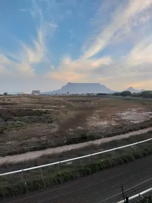 a road in a field with a mountain in the background at Apartment in Milnerton, Royal Ascot, Cape Town in Cape Town
