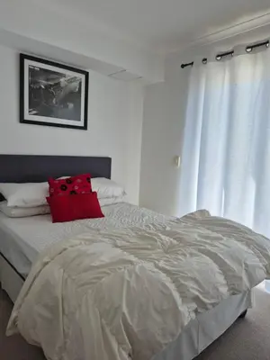 a bedroom with a bed with a red pillow on it at Apartment in Milnerton, Royal Ascot, Cape Town in Cape Town