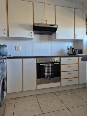 a kitchen with white cabinets and a stove top oven at Apartment in Milnerton, Royal Ascot, Cape Town in Cape Town