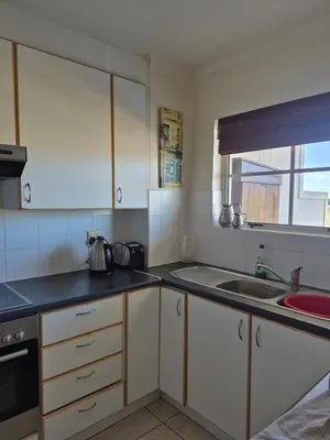 a kitchen with white cabinets and a sink at Apartment in Milnerton, Royal Ascot, Cape Town in Cape Town