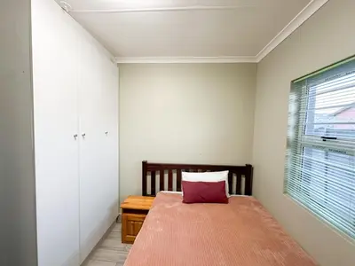a bedroom with a bed with a red pillow on it at 29 on Windsor Rooms- in Camelot,Kuilsriver in Silver Sands