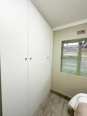 a bedroom with white cabinets and a window at 29 on Windsor Rooms- in Camelot,Kuilsriver in Silver Sands