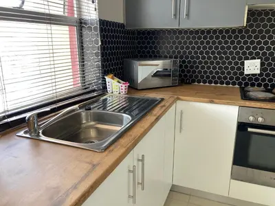 a kitchen counter with a sink and a microwave at Unit 1 GatherPoint Sleeps 6 Self-Catering Group in Belhar, Cape Town in Belhar