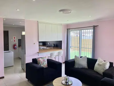 a living room with two couches and a kitchen at Unit 1 GatherPoint Sleeps 6 Self-Catering Group in Belhar, Cape Town in Belhar