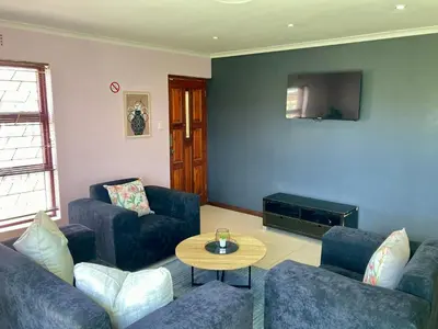 a living room with two blue couches and a table at Unit 1 GatherPoint Sleeps 6 Self-Catering Group in Belhar, Cape Town in Belhar