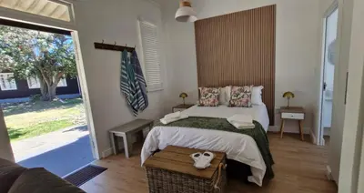 a bedroom with a bed and a large window at The Barracks at Brigadoon Village in Bettyʼs Bay