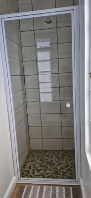 a shower with a glass door in a bathroom at The Barracks at Brigadoon Village in Bettyʼs Bay