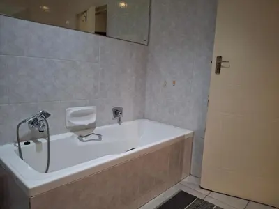 a bathroom with a tub and a mirror and a door at Spacious Suite Somerset West in Somerset West