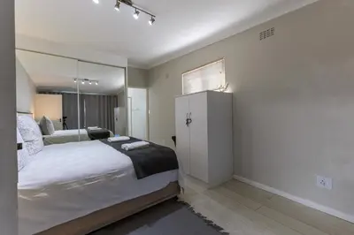 a bedroom with a large bed and a mirror at Fleurpark 6 in Gordonʼs Bay
